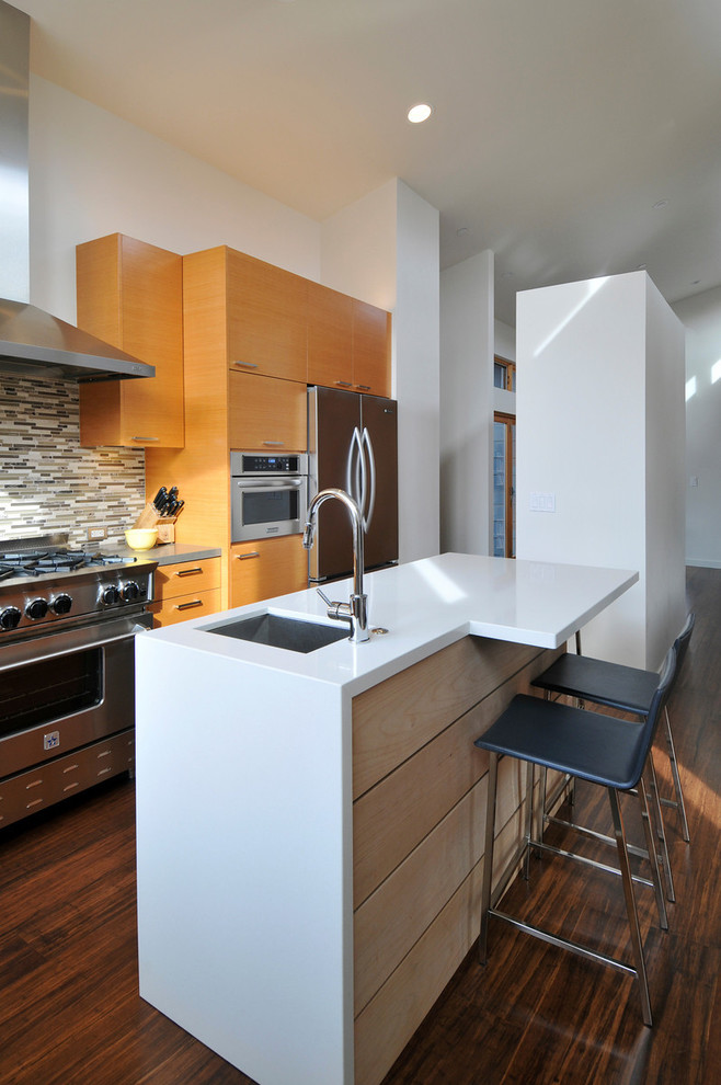 Modern l-shaped kitchen in San Francisco with a submerged sink, flat-panel cabinets, medium wood cabinets, matchstick tiled splashback, stainless steel appliances, an island, engineered stone countertops, multi-coloured splashback, medium hardwood flooring and brown floors.