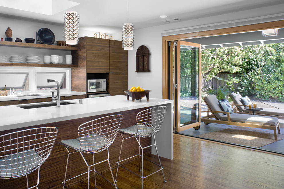 Example of a minimalist single-wall medium tone wood floor and brown floor eat-in kitchen design in San Francisco with flat-panel cabinets, medium tone wood cabinets, an island, quartz countertops and stainless steel appliances