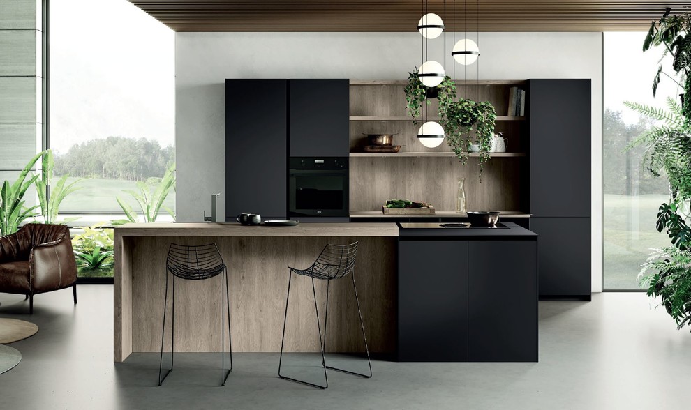 На фото: параллельная кухня-гостиная среднего размера в стиле модернизм с накладной мойкой, плоскими фасадами, черными фасадами, деревянной столешницей, черной техникой, бетонным полом, островом, серым полом и коричневой столешницей с