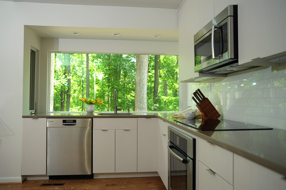 Foto på ett mellanstort funkis kök, med en enkel diskho, släta luckor, vita skåp, bänkskiva i kvarts, vitt stänkskydd, stänkskydd i glaskakel, rostfria vitvaror och ljust trägolv