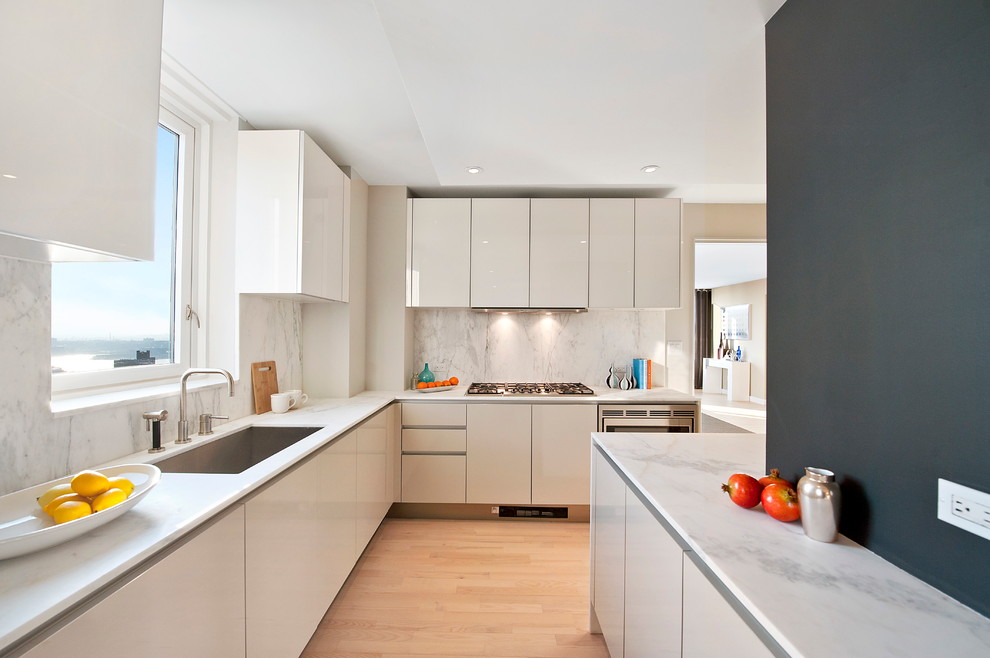 Стильный дизайн: кухня в стиле модернизм с врезной мойкой, плоскими фасадами, белыми фасадами, белым фартуком и акцентной стеной - последний тренд