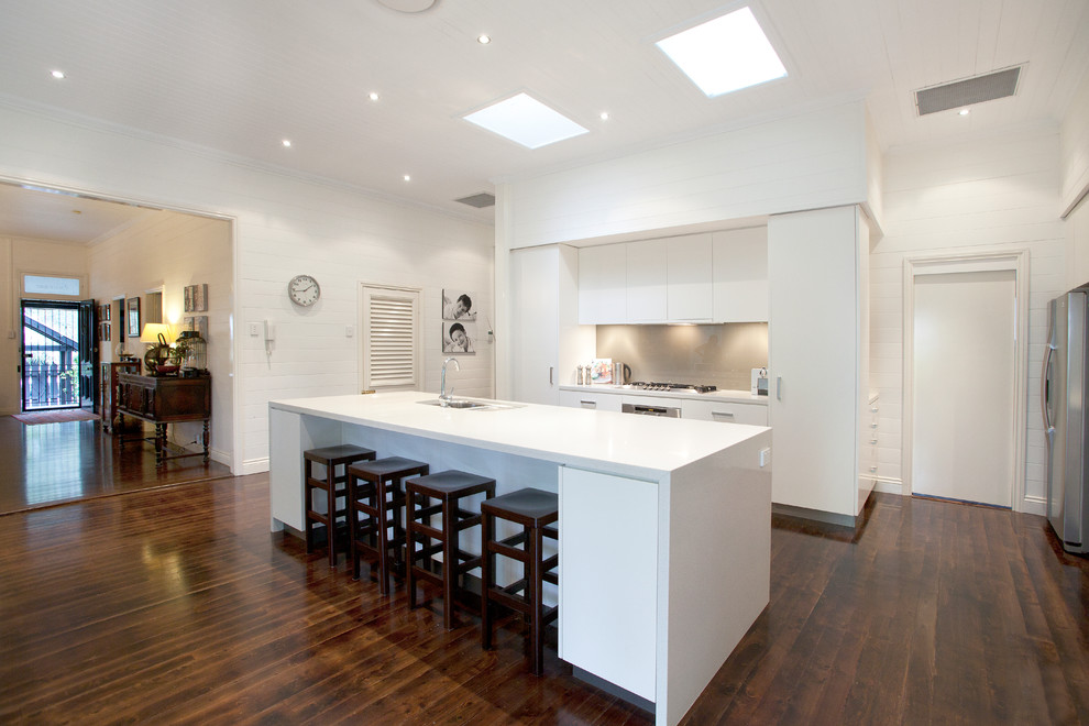 Inspiration for a large contemporary galley kitchen in Brisbane with a double-bowl sink, white cabinets, engineered stone countertops, glass sheet splashback, stainless steel appliances, dark hardwood flooring and an island.