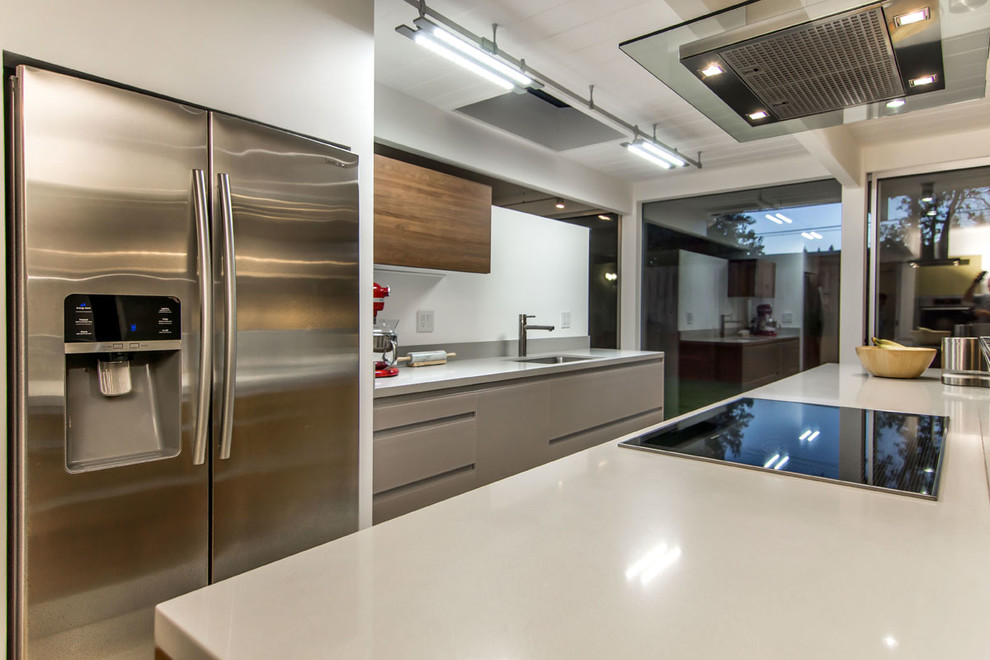 Esempio di una piccola cucina moderna con lavello sottopiano, ante lisce, ante grigie, top in superficie solida, paraspruzzi bianco, elettrodomestici in acciaio inossidabile e pavimento in gres porcellanato
