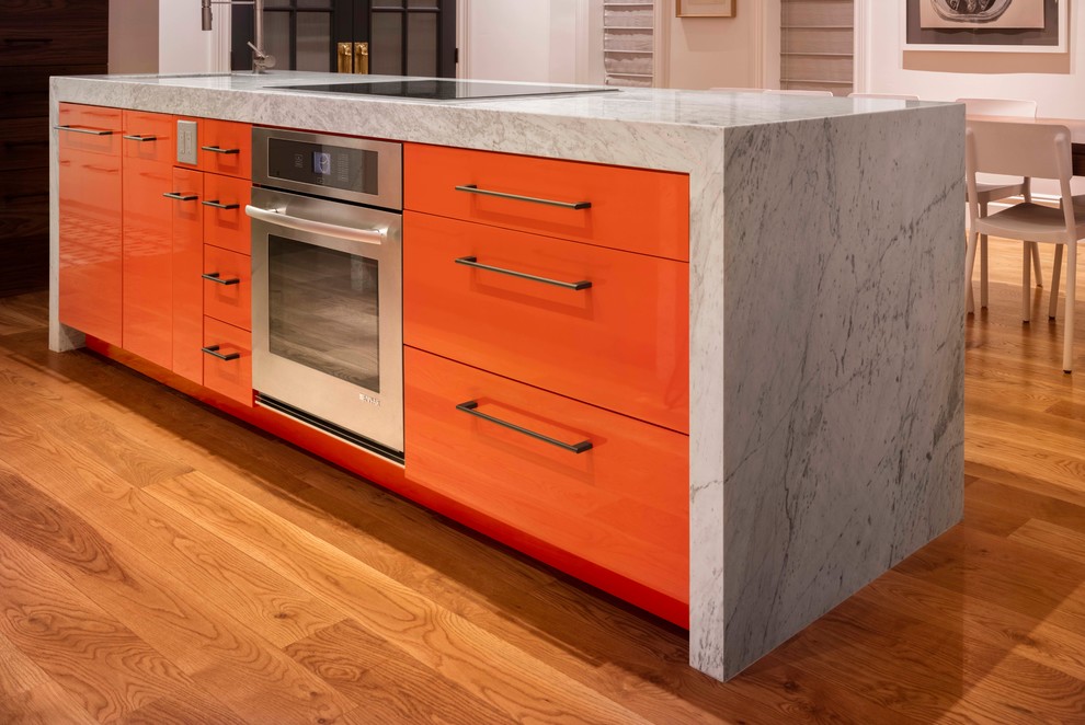 Mid-sized minimalist galley medium tone wood floor open concept kitchen photo in Denver with two islands, an undermount sink, flat-panel cabinets, orange cabinets, marble countertops and stainless steel appliances