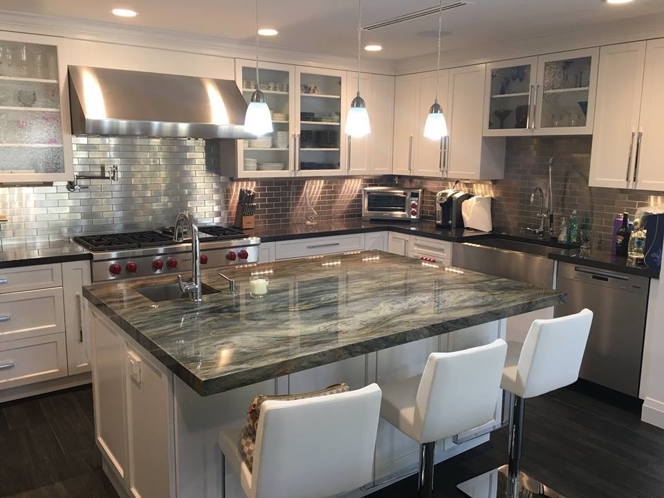 Kitchen - mid-sized contemporary l-shaped kitchen idea in Miami with a farmhouse sink, shaker cabinets, white cabinets, quartzite countertops, metallic backsplash, stainless steel appliances and an island