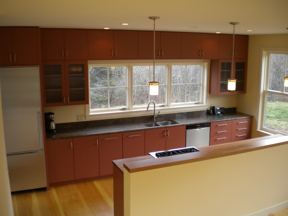 Inspiration for a medium sized modern galley kitchen/diner in Portland Maine with a double-bowl sink, flat-panel cabinets, red cabinets, soapstone worktops, white splashback, stainless steel appliances, light hardwood flooring and an island.