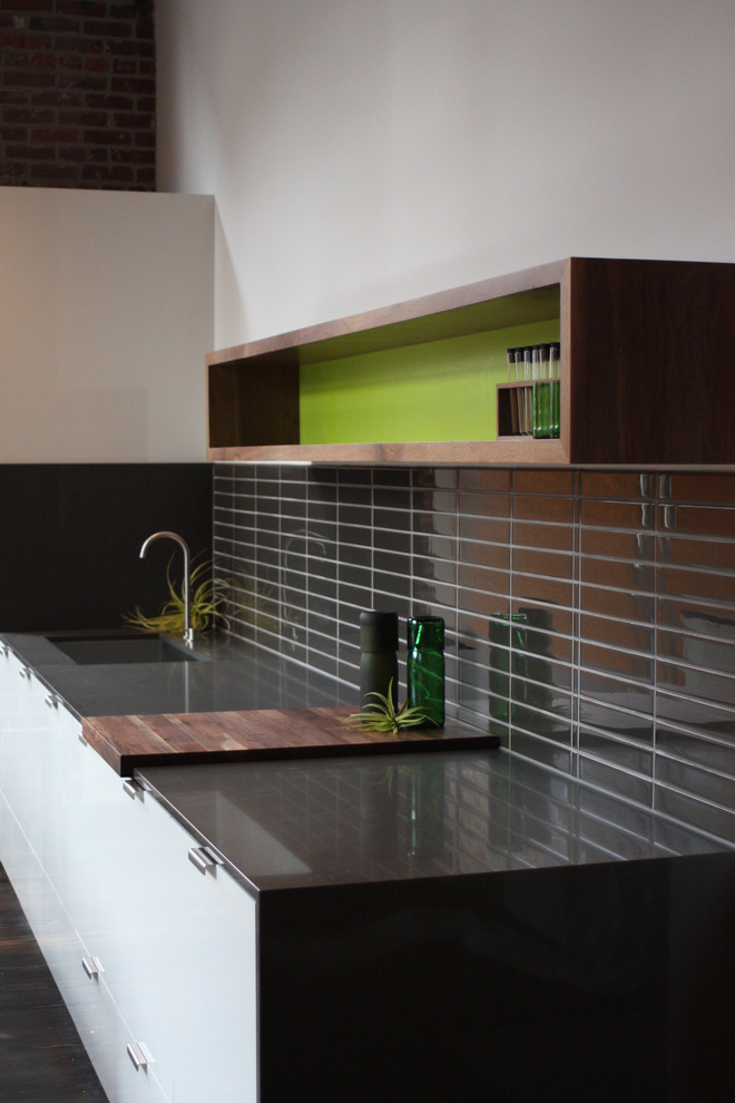 Modern inredning av ett mellanstort linjärt kök och matrum, med en undermonterad diskho, släta luckor, vita skåp, bänkskiva i kvarts, grått stänkskydd, stänkskydd i mosaik, rostfria vitvaror och mörkt trägolv