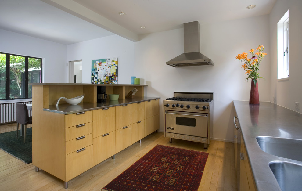 ワシントンD.C.にあるモダンスタイルのおしゃれなキッチン (シルバーの調理設備、ステンレスカウンター、一体型シンク、フラットパネル扉のキャビネット、中間色木目調キャビネット) の写真