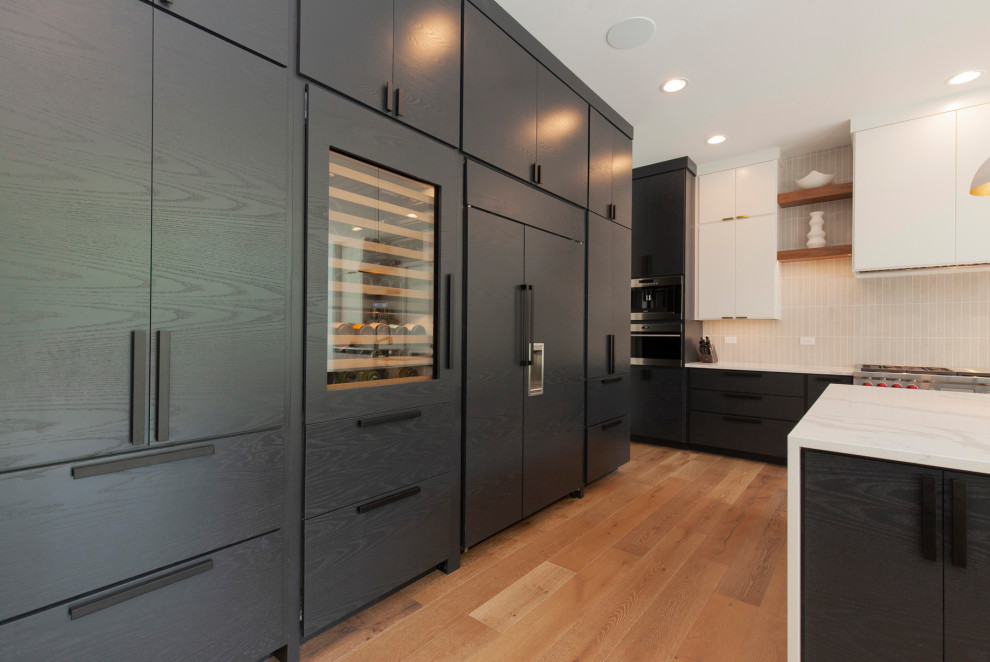 Eat-in kitchen - large modern l-shaped light wood floor and brown floor eat-in kitchen idea in Chicago with an undermount sink, flat-panel cabinets, black cabinets, quartz countertops, beige backsplash, subway tile backsplash, paneled appliances, an island and white countertops