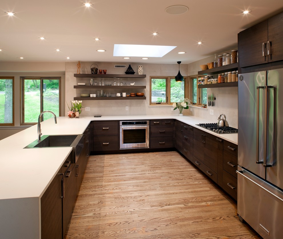 Modern inredning av ett stort u-kök, med en rustik diskho, bänkskiva i kvarts, rostfria vitvaror och mellanmörkt trägolv
