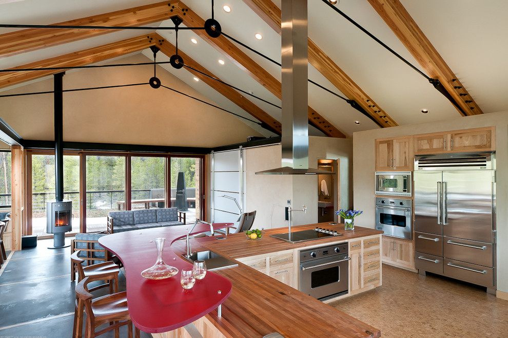 Стильный дизайн: кухня-гостиная в стиле модернизм с деревянной столешницей, светлыми деревянными фасадами и техникой из нержавеющей стали - последний тренд