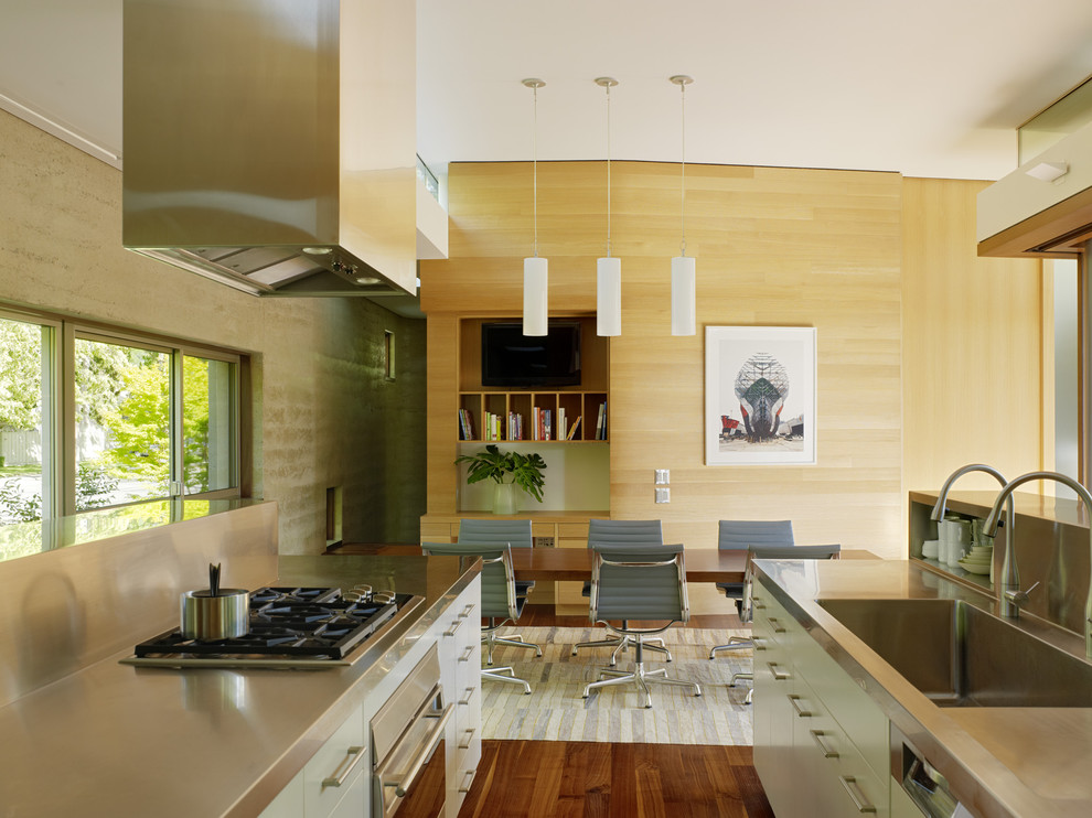 Example of a minimalist galley eat-in kitchen design in San Francisco with stainless steel countertops, an integrated sink, flat-panel cabinets, metallic backsplash, metal backsplash and stainless steel appliances