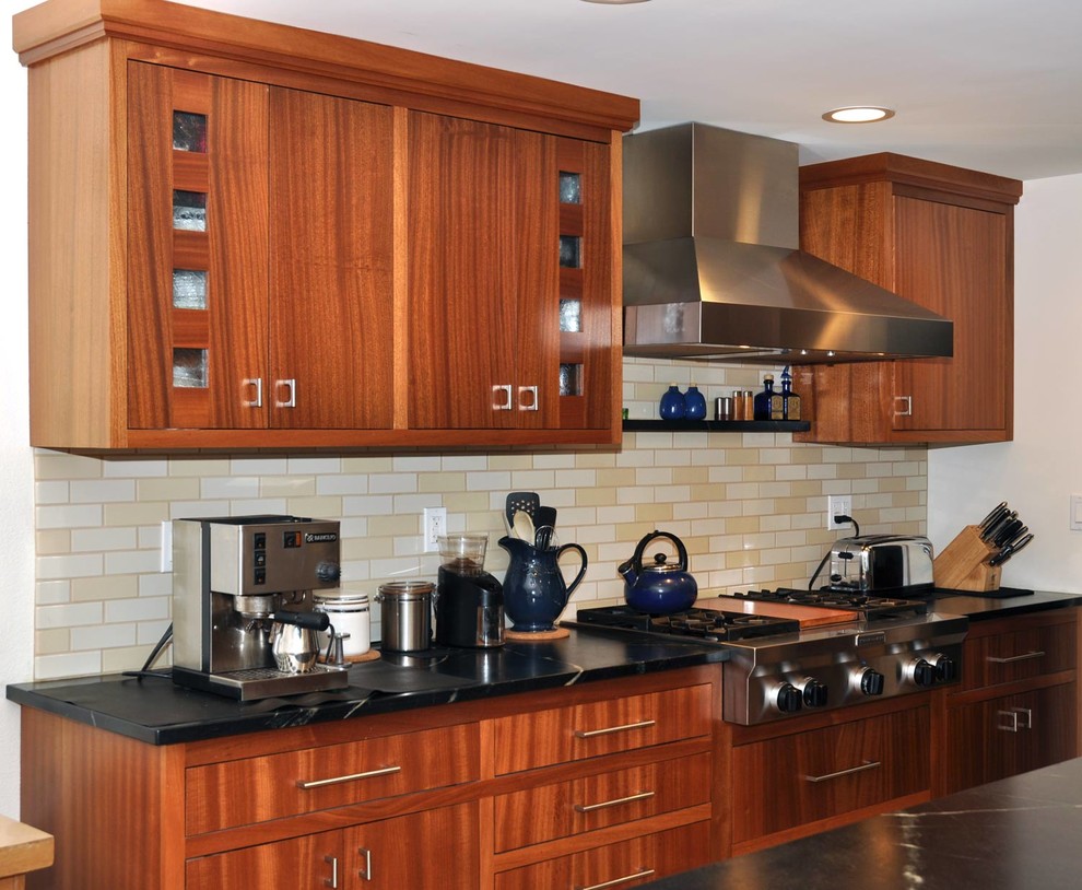 Exemple d'une cuisine américaine moderne en bois brun de taille moyenne avec un évier posé, un plan de travail en stéatite, une crédence en céramique, un électroménager noir, un sol en calcaire et îlot.