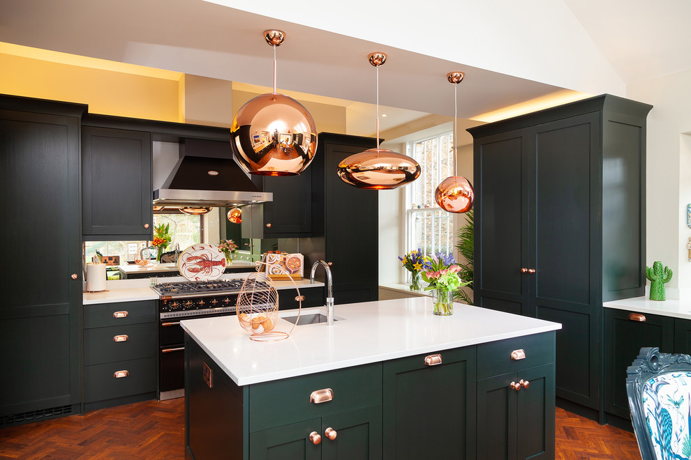 Klassische Küche mit Waschbecken, Schrankfronten im Shaker-Stil, grünen Schränken, Rückwand aus Spiegelfliesen, braunem Holzboden, Kücheninsel und weißer Arbeitsplatte in Sonstige
