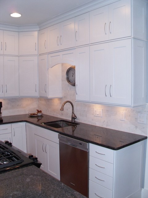 Bild på ett avskilt, mellanstort funkis l-kök, med en undermonterad diskho, skåp i shakerstil, vita skåp, granitbänkskiva, grått stänkskydd, stänkskydd i stenkakel, rostfria vitvaror, mellanmörkt trägolv och en köksö