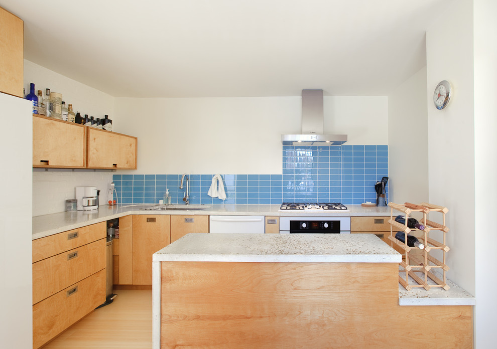 Idéer för ett modernt l-kök, med bänkskiva i betong, släta luckor, skåp i ljust trä, blått stänkskydd och vita vitvaror