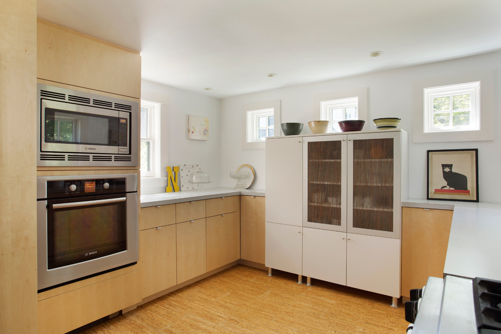 Immagine di una cucina contemporanea di medie dimensioni con ante di vetro, ante in legno scuro, elettrodomestici in acciaio inossidabile, lavello sottopiano, top in laminato, paraspruzzi bianco, pavimento in bambù e penisola