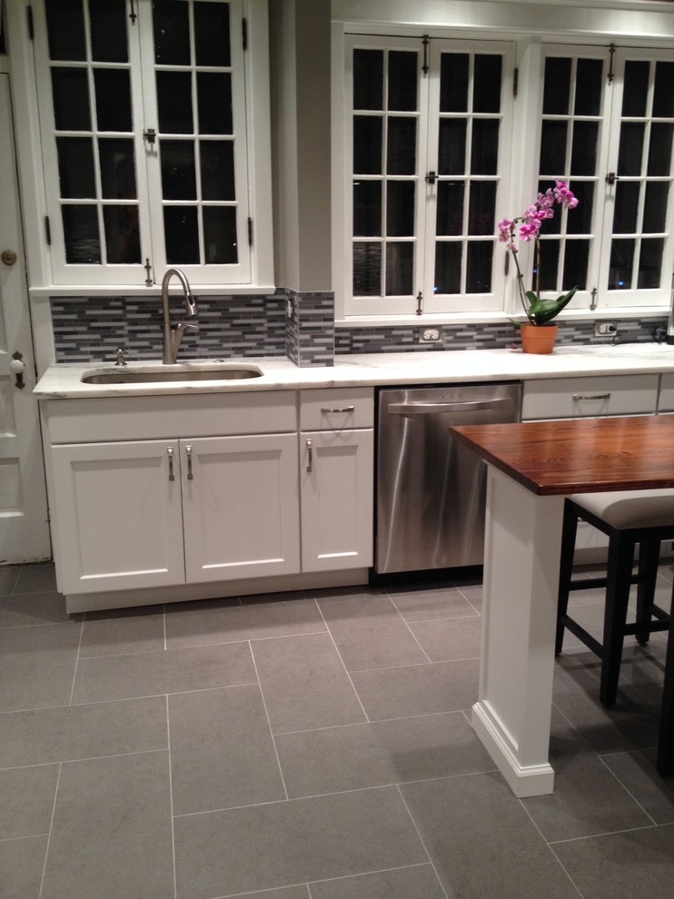 Exempel på ett modernt kök och matrum, med en undermonterad diskho, skåp i shakerstil, vita skåp, marmorbänkskiva, grått stänkskydd, stänkskydd i glaskakel, rostfria vitvaror och klinkergolv i porslin
