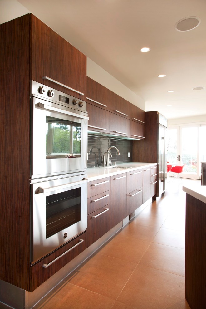 Inspiration for a large modern galley eat-in kitchen remodel in San Francisco with an integrated sink, flat-panel cabinets, medium tone wood cabinets, quartz countertops, black backsplash, ceramic backsplash, stainless steel appliances and an island