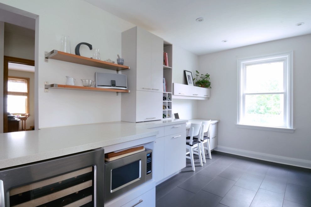 Modelo de cocina moderna con electrodomésticos de acero inoxidable, armarios con paneles lisos y puertas de armario blancas