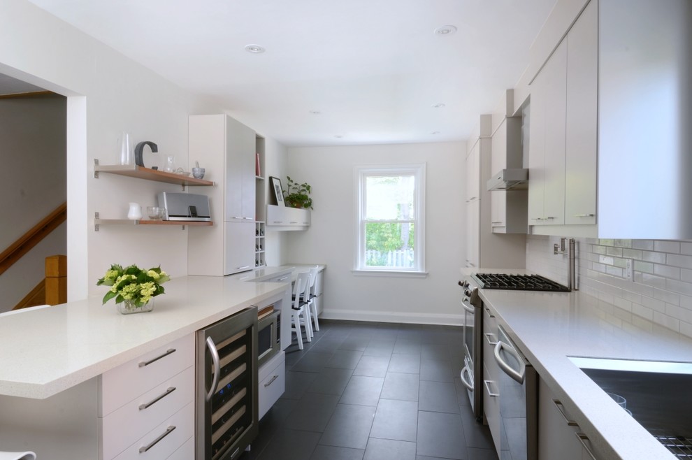 Ejemplo de cocina lineal moderna con salpicadero de azulejos tipo metro, fregadero bajoencimera, electrodomésticos de acero inoxidable, salpicadero blanco y suelo negro