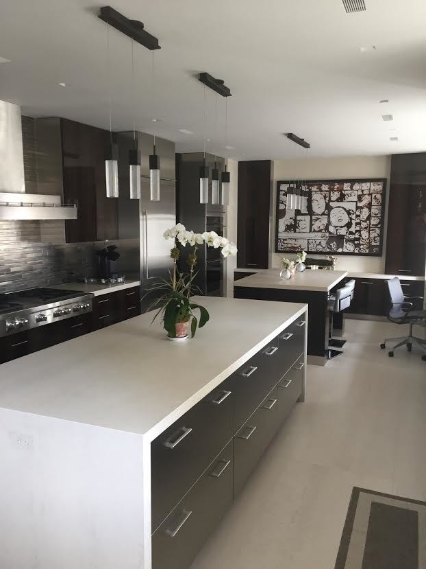This is an example of a large contemporary galley enclosed kitchen in New York with flat-panel cabinets, dark wood cabinets, composite countertops, grey splashback, matchstick tiled splashback, stainless steel appliances, porcelain flooring, multiple islands and beige floors.