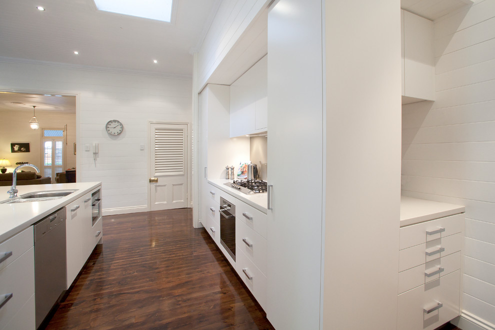 This is an example of a large contemporary galley open plan kitchen in Brisbane with flat-panel cabinets, white cabinets, an island, a double-bowl sink, engineered stone countertops, grey splashback, glass sheet splashback, stainless steel appliances and dark hardwood flooring.