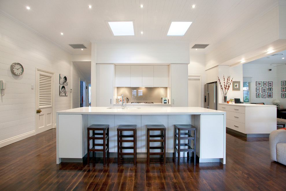Example of a large trendy galley dark wood floor open concept kitchen design in Brisbane with flat-panel cabinets, white cabinets, gray backsplash, glass sheet backsplash, stainless steel appliances, an island, a double-bowl sink and quartz countertops