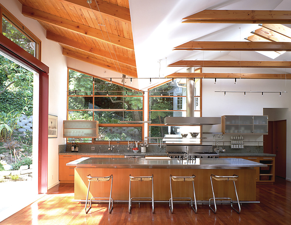 Immagine di una cucina parallela moderna con top in acciaio inossidabile, ante lisce e ante in legno scuro