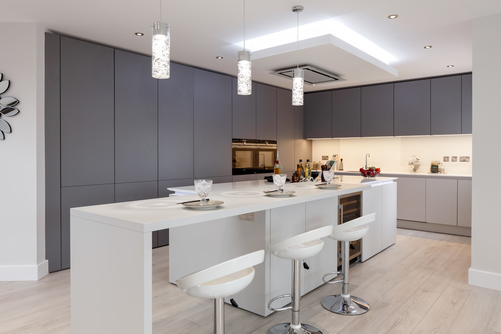 Foto di una cucina design di medie dimensioni con ante lisce, ante grigie, top in superficie solida, paraspruzzi bianco, elettrodomestici da incasso, parquet chiaro e pavimento beige