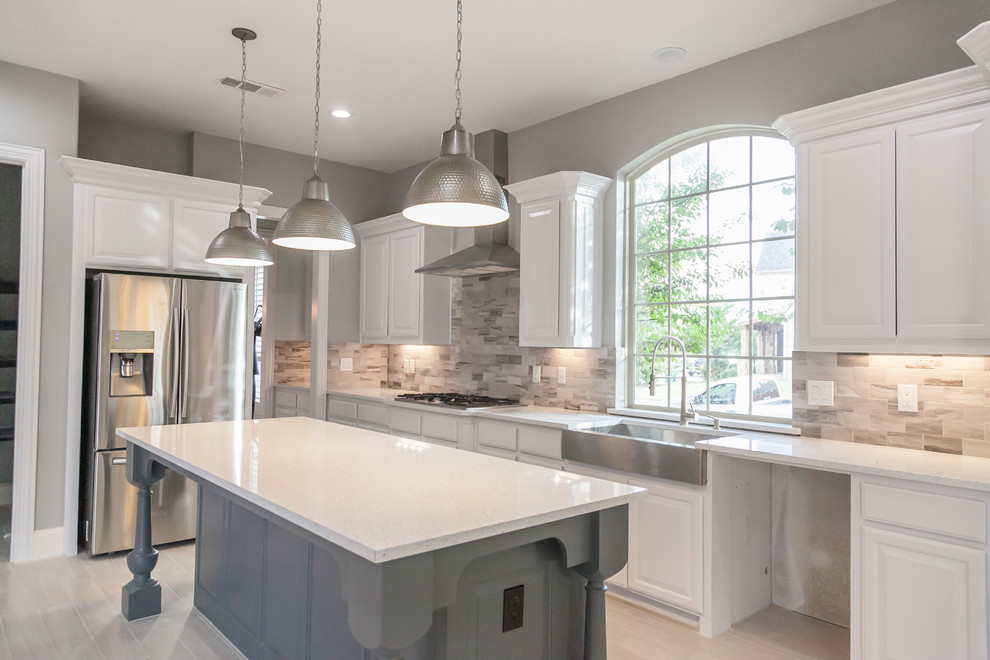 Large minimalist single-wall bamboo floor open concept kitchen photo in Dallas with a farmhouse sink, white cabinets, quartzite countertops, gray backsplash, ceramic backsplash, stainless steel appliances, an island and raised-panel cabinets