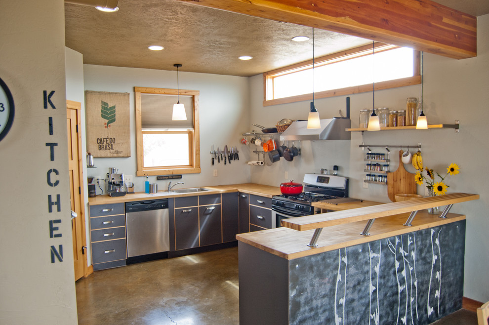 На фото: отдельная, п-образная кухня среднего размера в стиле кантри с одинарной мойкой, плоскими фасадами, серыми фасадами, деревянной столешницей, техникой из нержавеющей стали, бетонным полом и полуостровом