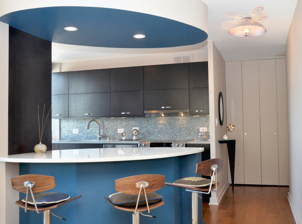 Modelo de cocina minimalista con salpicadero con mosaicos de azulejos, electrodomésticos de acero inoxidable, salpicadero azul y armarios con paneles lisos