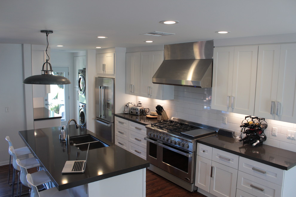 Mid-sized minimalist galley dark wood floor eat-in kitchen photo in Los Angeles with an undermount sink, shaker cabinets, white cabinets, quartz countertops, white backsplash, subway tile backsplash, stainless steel appliances and an island