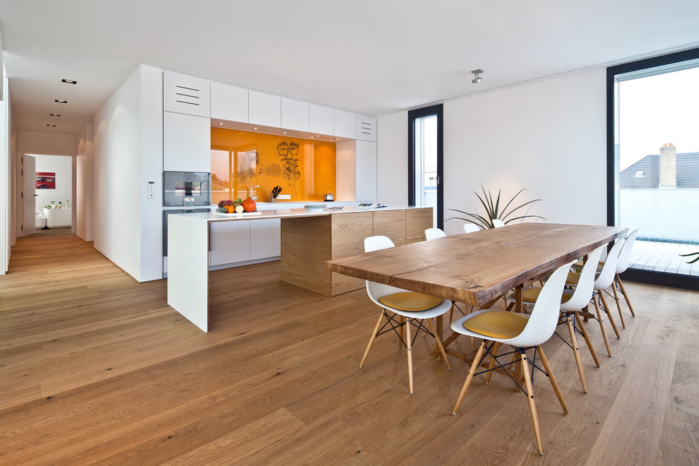 Einzeilige Moderne Wohnküche mit braunem Holzboden, flächenbündigen Schrankfronten, weißen Schränken, Küchenrückwand in Orange, Küchengeräten aus Edelstahl und Kücheninsel in Miami