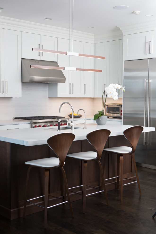 Idées déco pour une cuisine classique en L avec un placard à porte shaker, des portes de placard blanches, une crédence blanche, un électroménager en acier inoxydable, parquet foncé, îlot et plan de travail en marbre.