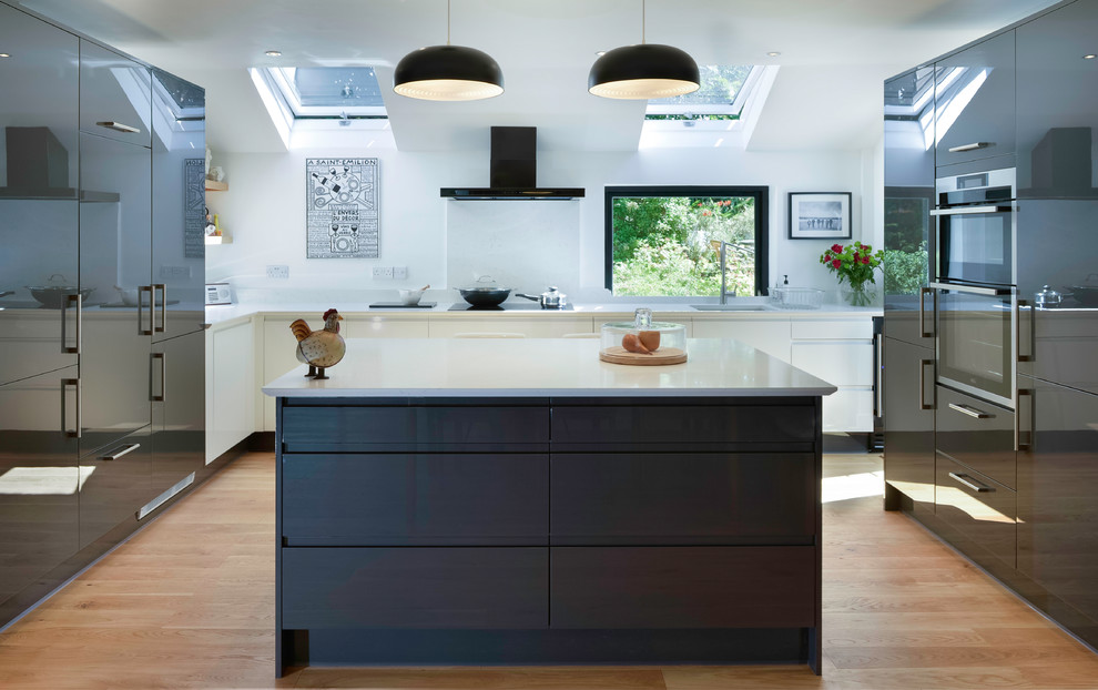 Exempel på ett mellanstort modernt vit vitt kök, med grå skåp, granitbänkskiva, vitt stänkskydd, ljust trägolv, en köksö, beiget golv, en undermonterad diskho och släta luckor