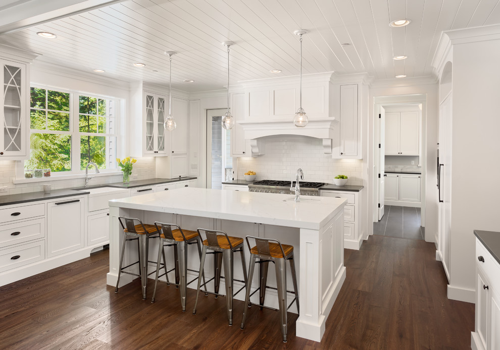 Large country u-shaped dark wood floor and brown floor eat-in kitchen photo in DC Metro with a farmhouse sink, recessed-panel cabinets, white cabinets, quartz countertops, white backsplash, subway tile backsplash, paneled appliances, an island and gray countertops