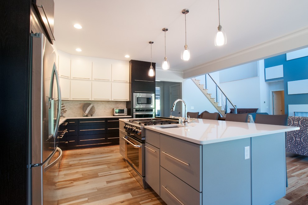 Ejemplo de cocina minimalista grande con armarios con paneles lisos, electrodomésticos de acero inoxidable, suelo de madera clara y una isla