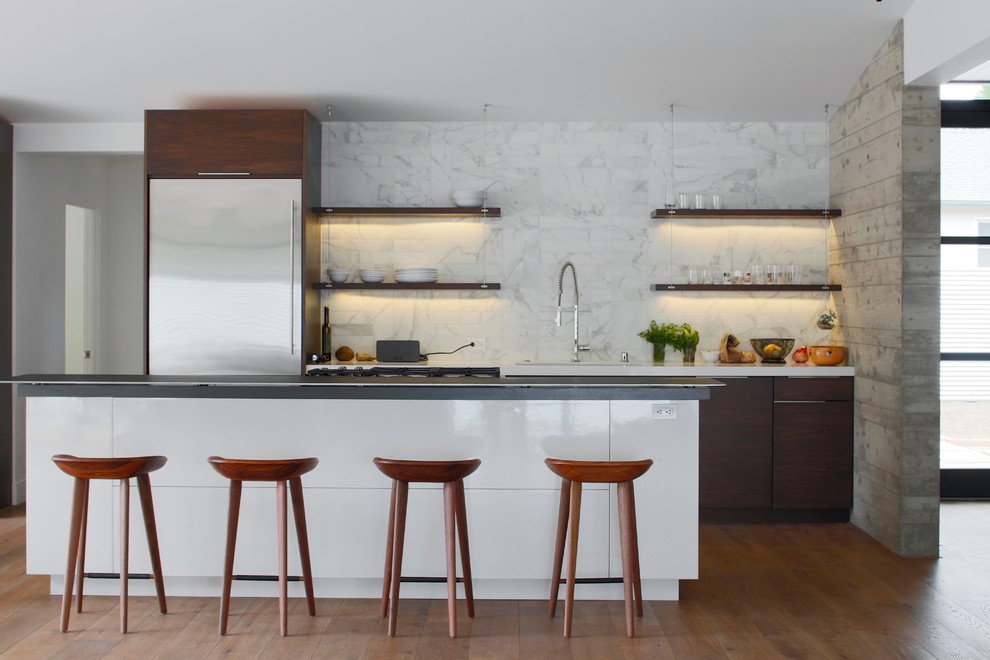 Inspiration pour une cuisine américaine parallèle minimaliste en bois foncé avec une crédence blanche et un électroménager en acier inoxydable.