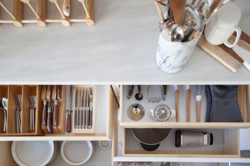 Foto på ett mellanstort funkis u-kök, med vita skåp, marmorbänkskiva, vitt stänkskydd, stänkskydd i keramik och rostfria vitvaror