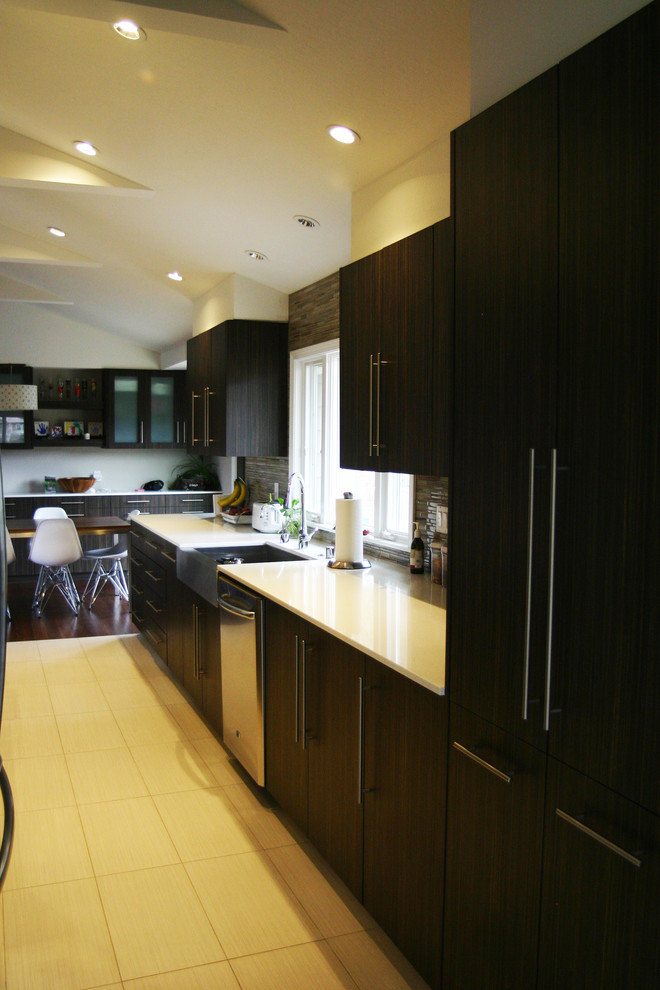 This is an example of a large modern galley kitchen/diner in San Francisco with a belfast sink, flat-panel cabinets, dark wood cabinets, engineered stone countertops, multi-coloured splashback, glass tiled splashback, stainless steel appliances, bamboo flooring and a breakfast bar.