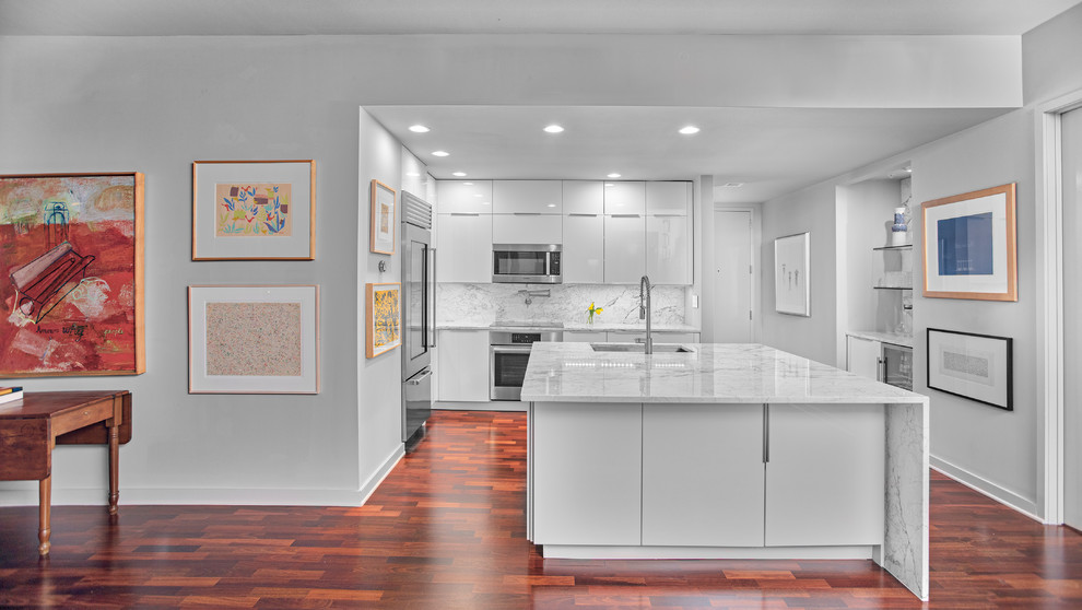 Exempel på ett litet modernt kök, med en undermonterad diskho, släta luckor, vita skåp, marmorbänkskiva, vitt stänkskydd, stänkskydd i marmor, rostfria vitvaror, mellanmörkt trägolv, en köksö och brunt golv