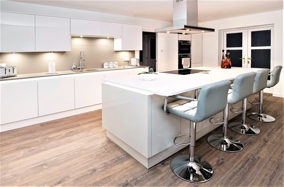 Photo of a modern kitchen in Other with a built-in sink, flat-panel cabinets, white cabinets, beige splashback, black appliances, medium hardwood flooring, an island, brown floors and white worktops.
