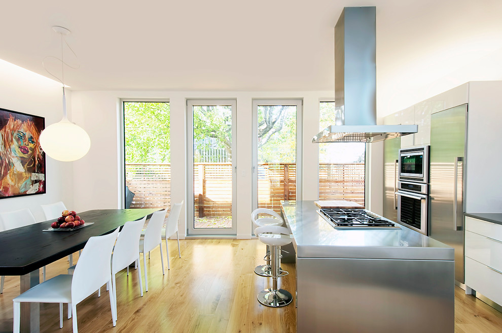 Zweizeilige Moderne Wohnküche mit flächenbündigen Schrankfronten, weißen Schränken, Edelstahl-Arbeitsplatte und Küchengeräten aus Edelstahl in Ottawa