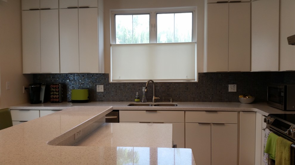 Foto på ett mellanstort funkis kök, med en köksö, luckor med glaspanel, vita skåp, bänkskiva i återvunnet glas, stänkskydd med metallisk yta, stänkskydd i glaskakel, rostfria vitvaror, en undermonterad diskho och mellanmörkt trägolv
