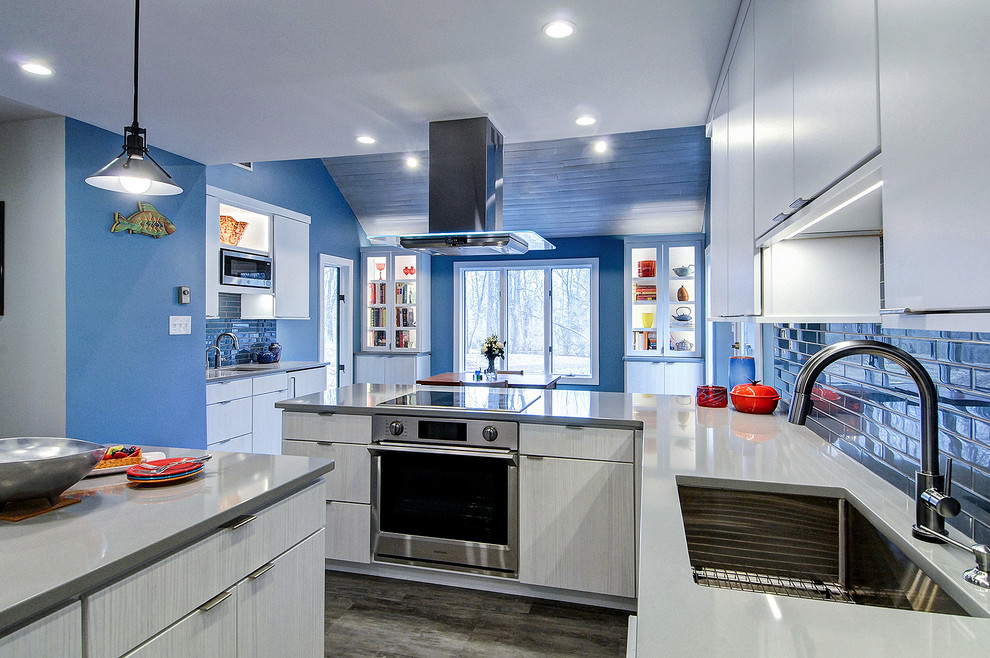Ejemplo de cocina moderna de tamaño medio con armarios con paneles lisos, puertas de armario blancas, encimera de cuarcita, salpicadero azul, salpicadero de azulejos de vidrio, electrodomésticos con paneles, una isla y encimeras grises