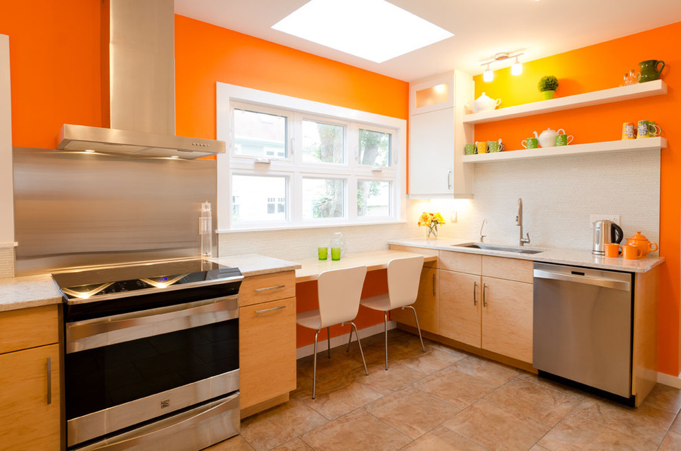 Exempel på ett stort modernt kök, med en undermonterad diskho, gula skåp, granitbänkskiva, vitt stänkskydd, rostfria vitvaror, klinkergolv i keramik, släta luckor, stänkskydd i metallkakel och beiget golv