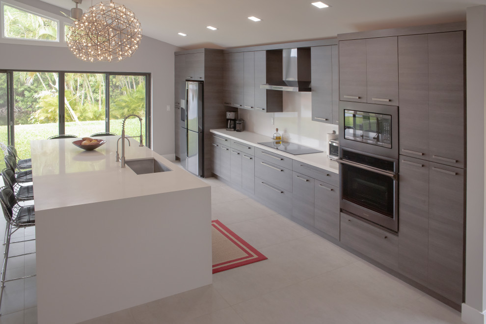This is an example of a modern grey and cream kitchen/diner in Miami with flat-panel cabinets, medium wood cabinets, engineered stone countertops, white splashback, an island and white worktops.