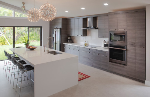 Kitchens and Bathrooms: modern gray wood flat-panel kitchen with long cabinet wall, white quartz waterfall island, globe pendants, and stainless appliances.